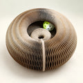 CurlNest accordion paper cat scratcher in a circular shape with its green-and-white play ball.