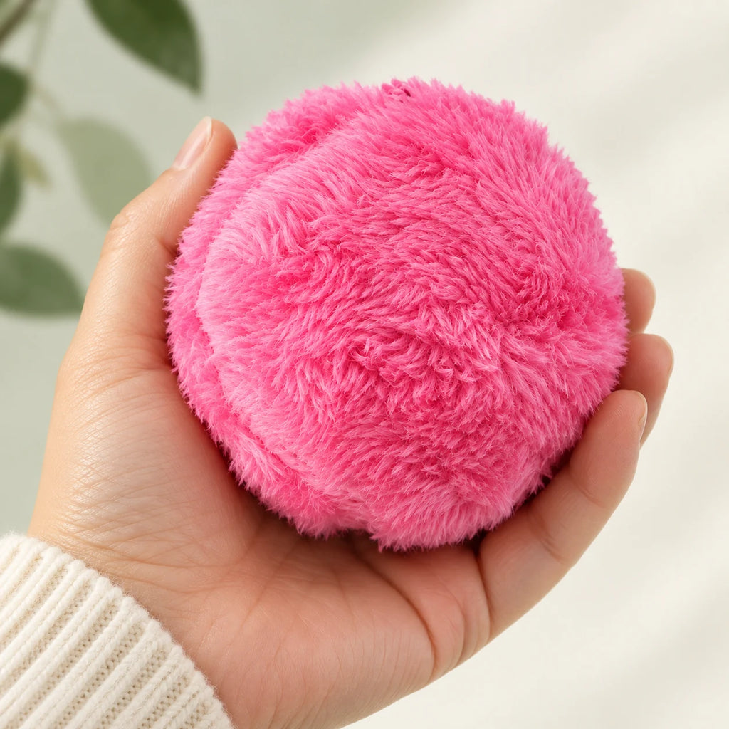 RoamRoll pink cloth-covered ball held in an adult hand for scale.